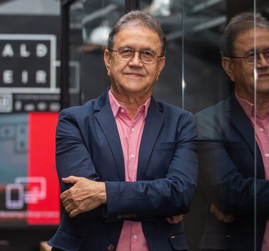 Xavier Fritsch em pé, usando blazer azul-marinho e camisa rosa